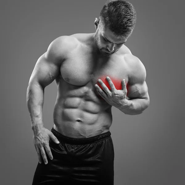 Homem sem camisa muscular com dor no coração sobre fundo cinza . — Fotografia de Stock