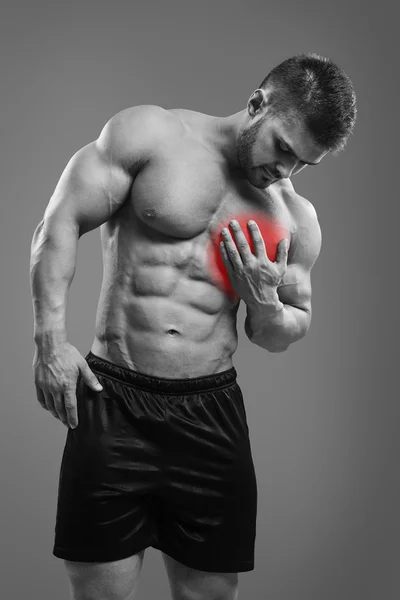 Hombre musculoso sin camisa con dolor en el pecho sobre fondo gris — Foto de Stock