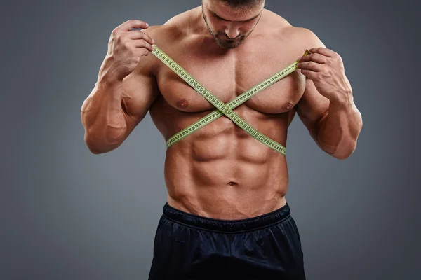 Bodybuilder measuring waist with tape measure — Φωτογραφία Αρχείου