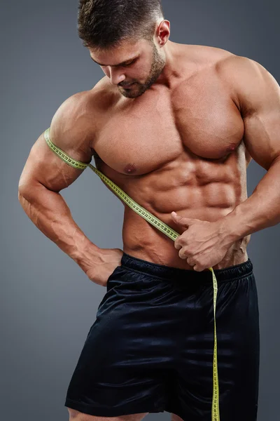 Bodybuilder measuring biceps with tape measure — Stock Photo, Image