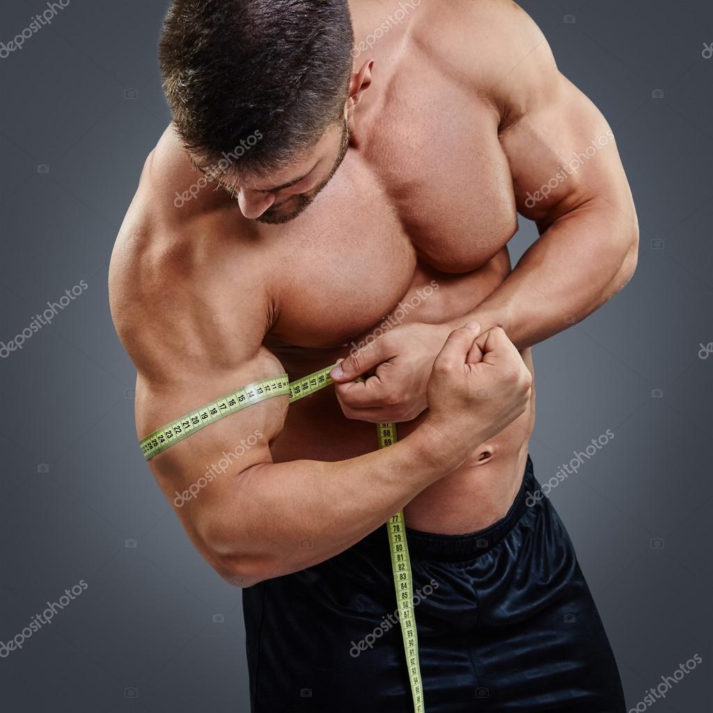 Bodybuilder measuring biceps with tape measure Stock Photo by ©kegfire