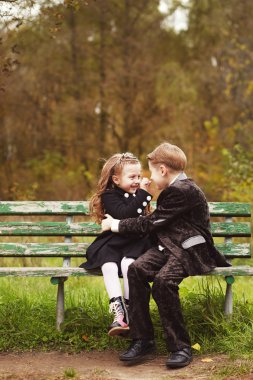 Cute little girl and boy hugging on bench