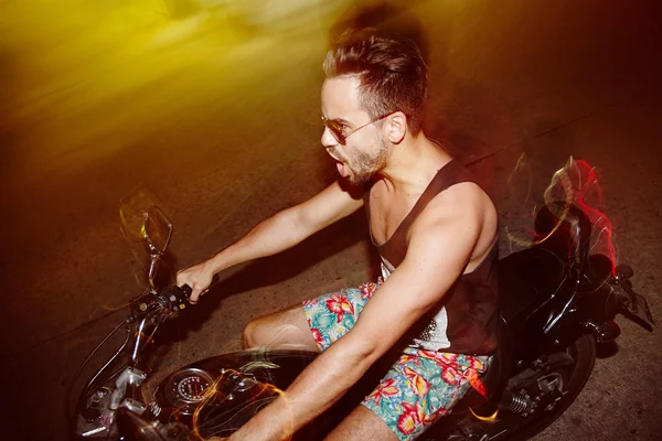 年轻男子骑自行车的人骑摩托车在夜晚的城市 — 图库照片