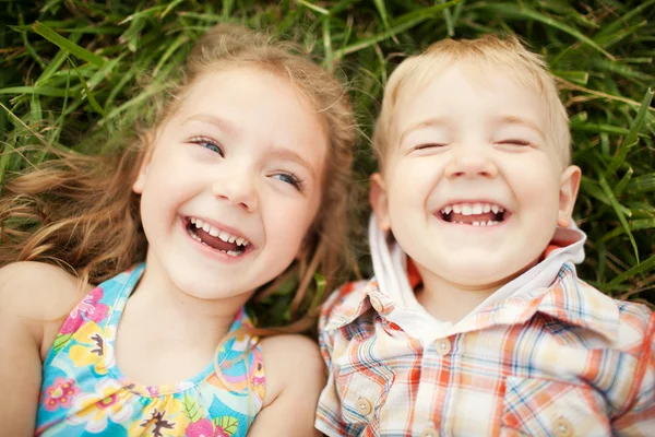 Bovenaanzicht van twee kinderen broer en zus liggen op gras — Stockfoto