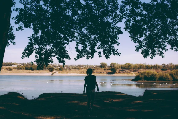 Silhuette de mujer joven caminando hacia un lago — Foto de Stock