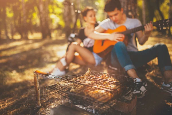 Pareja adolescente haciendo un picnic y tocando la guitarra — Foto de Stock