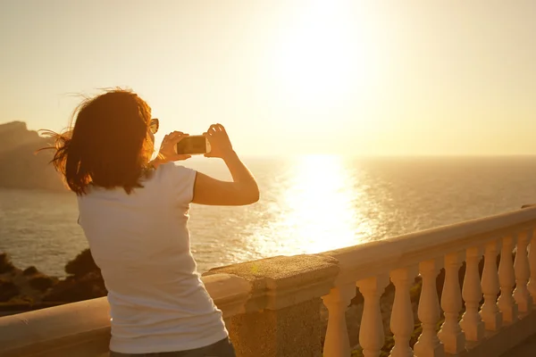 Jovem mulher tirando foto do pôr do sol — Fotografia de Stock