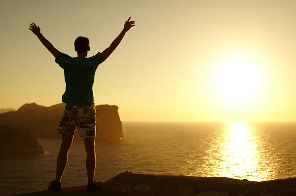 Silhouette di un uomo con le braccia alzate al tramonto Immagini Stock Royalty Free