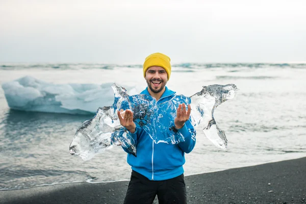 Joven sonriente sosteniendo un trozo de hielo — Foto de Stock