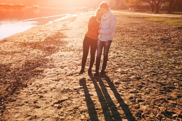 Retrato de pareja caminando juntos en una puesta de sol junto a un lago en una c — Foto de Stock