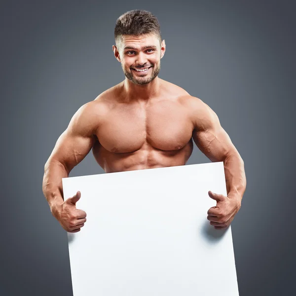 Atleta muscular segurando cartaz branco em branco — Fotografia de Stock