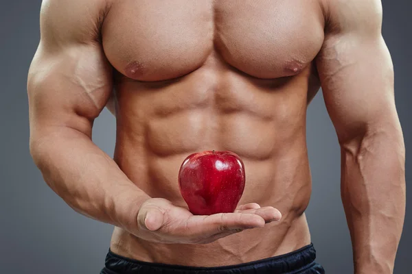 Mann hält einen frischen roten Apfel auf grauem Hintergrund. — Stockfoto