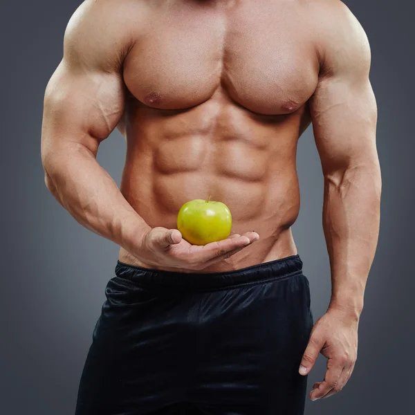 Hombre musculoso sin camisa sosteniendo una manzana fresca — Foto de Stock