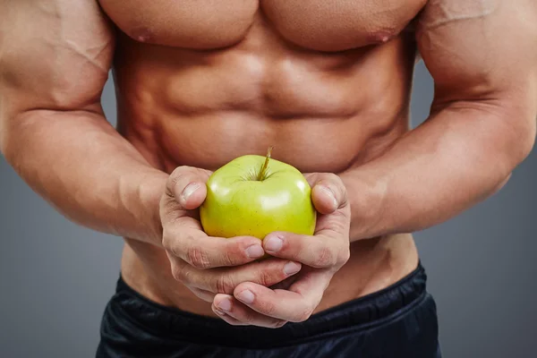 Fisicoculturista sin camisa sosteniendo una manzana — Foto de Stock