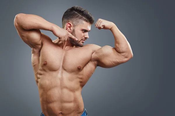 Muscular athletic man pointing to his biceps — Stock Photo, Image