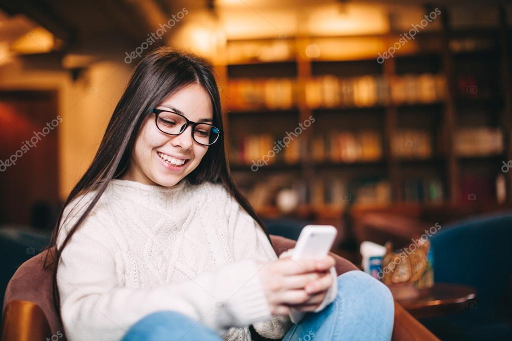 Positive and smiling young teenage girl texting