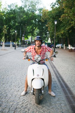 Beyaz scooter üzerinde oturan yakışıklı genç adam