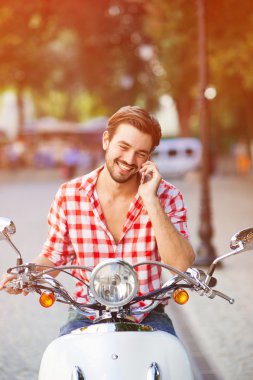 Bir scooter üzerinde gülümseyen atlatmışsınız genç adam