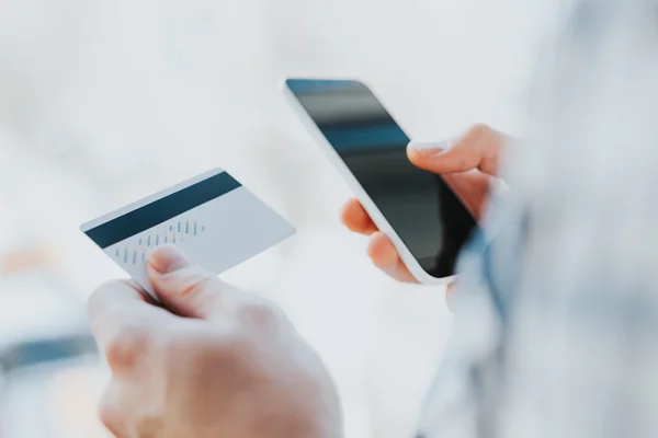 Young man hands holding credit card and using phone Stock Picture