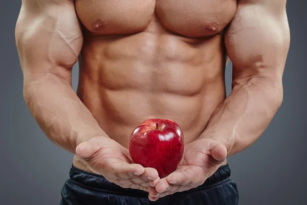 Торс из шести пакетов и красное яблоко в руках — стоковое фото