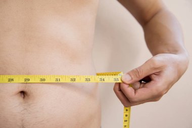 Göbekli ve elinde bant olan bir adam.