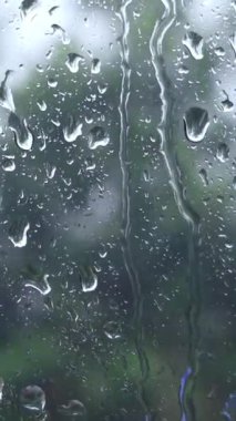 Yağmurlu havada pencere camındaki yağmur damlalarını kapat. Soyut su damlacıkları dokusu dengesiz bir atmosfer, sakin bir his ve hava, duygu ve mevsimsel kavramlar için doğal bir zemin yaratır..