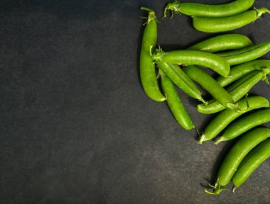 Koyu arkaplanda yeşil bezelye kabukları