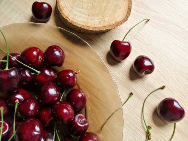 Kirazlar tabakta, biraz da masaya ve ahşap tezgahın yanına dağılmış.