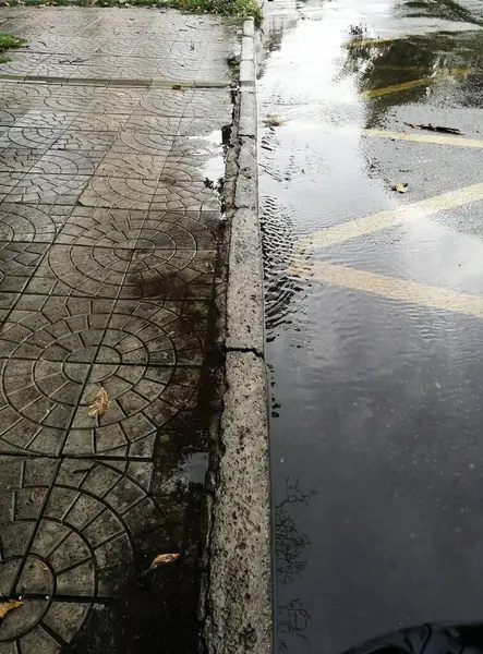 Väg, trottoar och pölar på asfalten efter regnet — Stockfoto