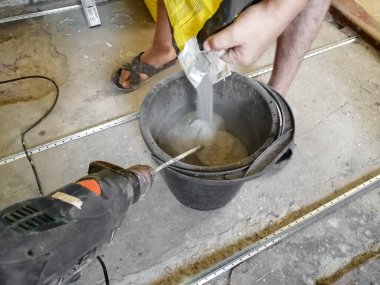 Bir adam çözeltiyi yoğurmak için bir kova zemin döker.