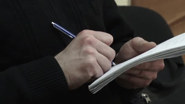 Handen - de man schrijft in een notitieblok. — Stockvideo