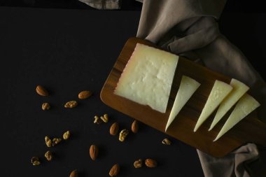 Kahverengi peçete, siyah arkaplan ve fotokopi alanının yanında Manchego peyniri resmi.