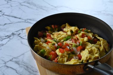 Meksika yumurtalarının tavada, kesme tahtasında, mermer masanın üstünde, fotokopi alanı ile yakın plan.