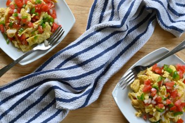 Çatallı, çizgili kumaşlı, ahşap masalı iki Meksika yumurtasının yatay üst çekimi.