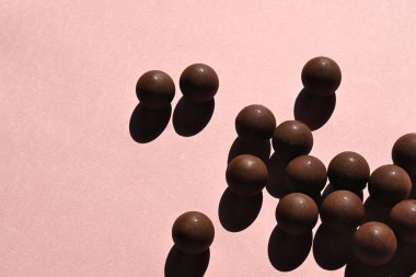 Sert gölgeli çikolata topları, pastel pembe arka plan. Uluslararası çikolata günü konsepti