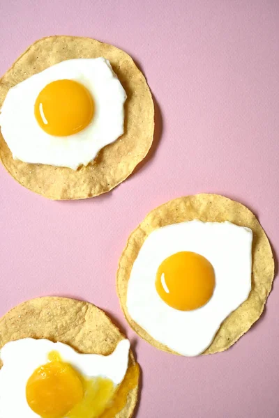 Τρία Τηγανητά Αυγά Ένα Σπασμένο Ροζ Φόντο — Φωτογραφία Αρχείου