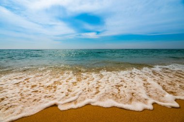 Temiz kumsalda yumuşak mavi okyanus dalgası