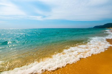 Temiz kumsalda yumuşak mavi okyanus dalgası