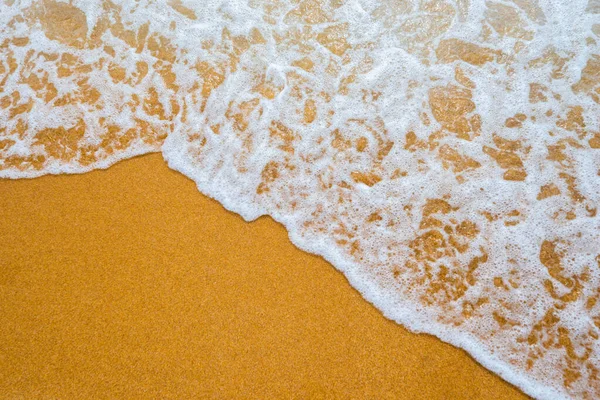 Soft blue ocean wave on clean sandy beach