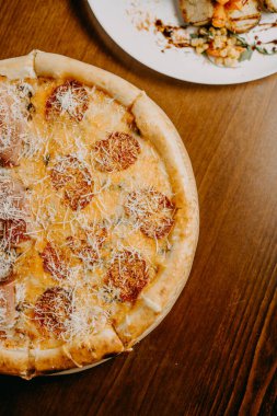 Lezzetli pizza ve pişirme malzemeleri siyah beton arka planda domates fesleğeni. Sıcak pizzanın en üst görüntüsü