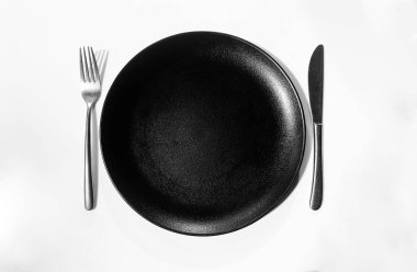 Bıçak ve Çatal, Temiz Siyah Tabak 'la beyaz Masa' nın ortasında. Modern Restoran kavramı arka planı