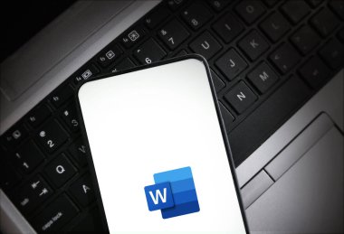 Cep telefonunda dizüstü bilgisayarın arka planında Microsoft Word logosu gösteriliyor illüstrasyon teknolojisi kavramı