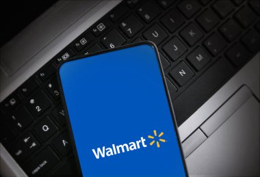 Walmart logosu akıllı telefon ekranında dizüstü bilgisayar klavyesinde resimli yayın teknolojisi ve perakende kavramlarında gösterilir