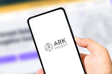 ARK Yatırım logosunu arka planda bulanık finansal grafiklerle gösteren akıllı telefon.