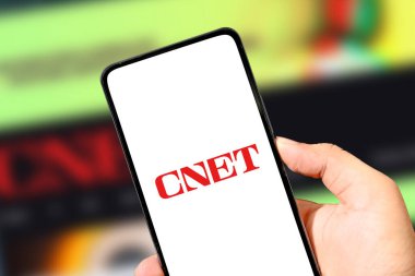 CNET logosunu renkli bulanık arkaplan illüstrasyonlu gösteren akıllı telefon.
