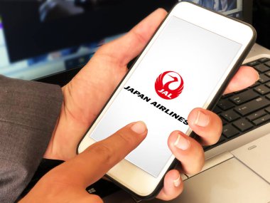 Arka planda dizüstü bilgisayarla Japon havayollarını kullanan bir adam. Editoryal Japon Havayolları konsepti