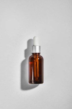 Kehribar damlatan cam şişe gri arka planda. Model