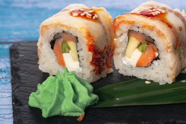 Suşi rulo, yılan balığı ve avokado, havyar, Philadelphia peyniri, unagi sosu ve susam tohumlu mavi arka plan suşi menüsünde. Japon yemeği..