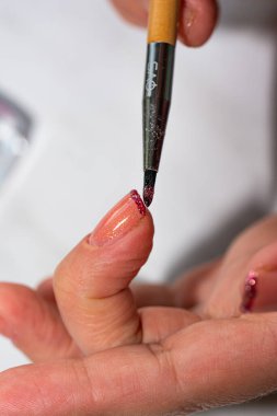 Tırnaklar için manikür boyası pembe, kurşun kalemle parıldayan kırmızı bir ceket çiziyor.