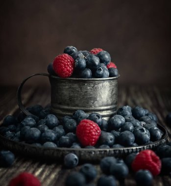 Bardakta böğürtlen. Koyu arkaplanda yabanmersini ve ahududu. Fotoğraf taşra tarzında. Kartpostal. 